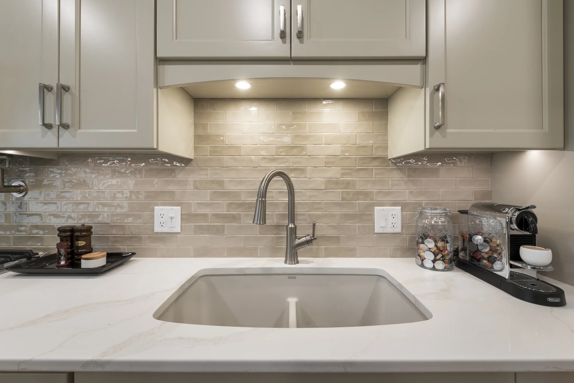 Undermount sink framed by neutral cabinetry and tile
