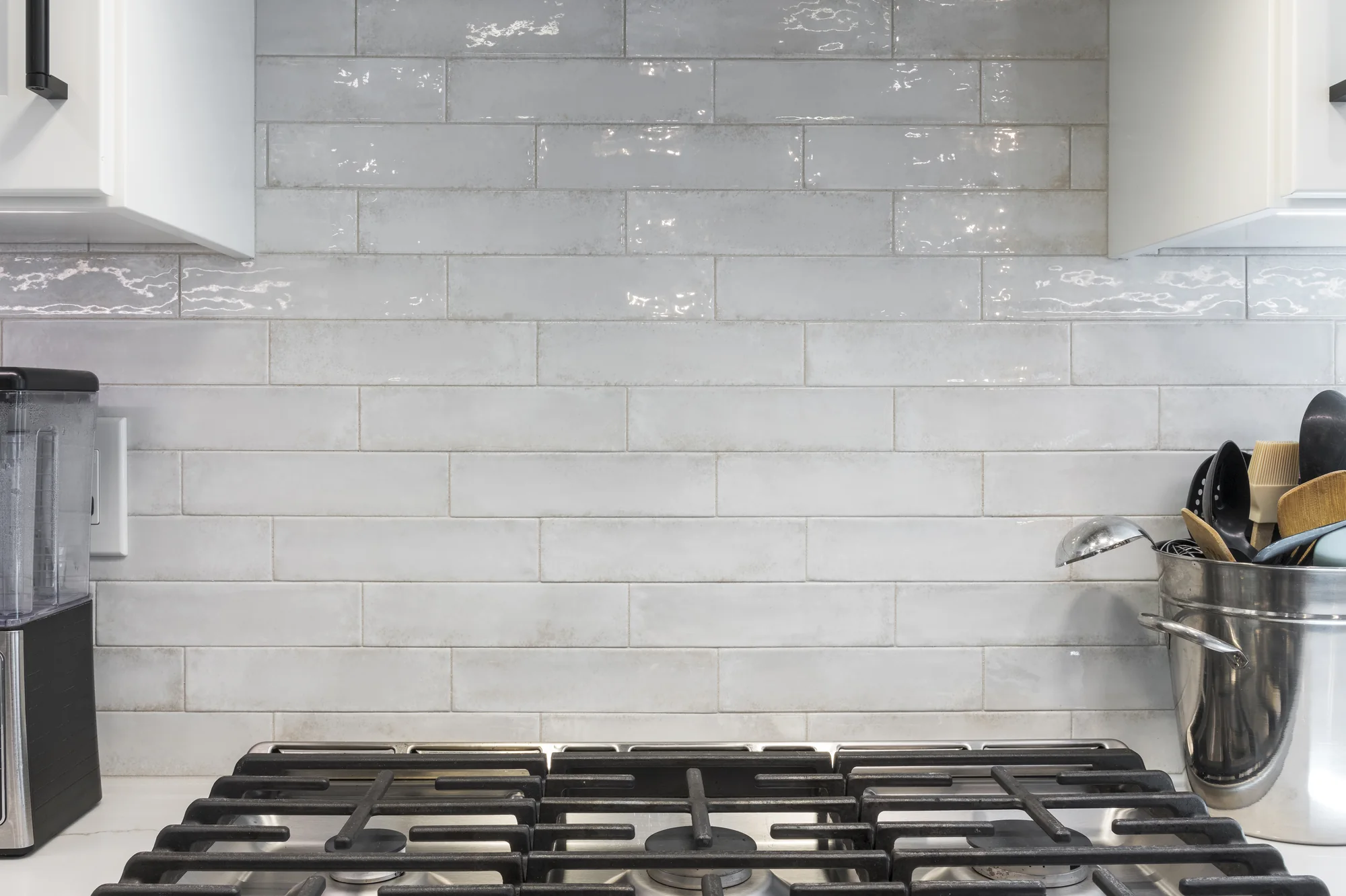 Soft white tile backsplash above the range