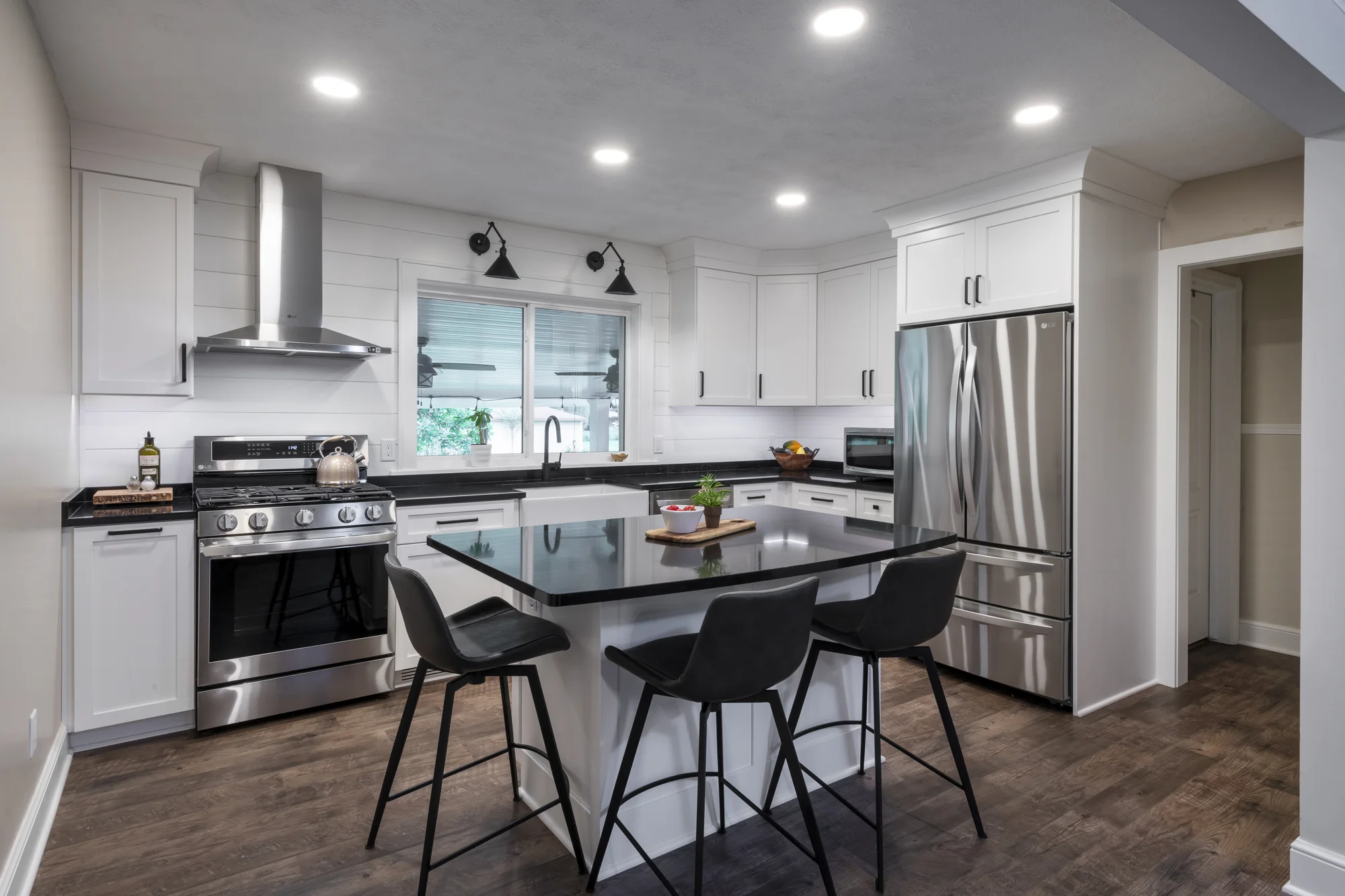 Modern farmhouse kitchen with white cabinetry, black countertops, and a large island in North Olmsted