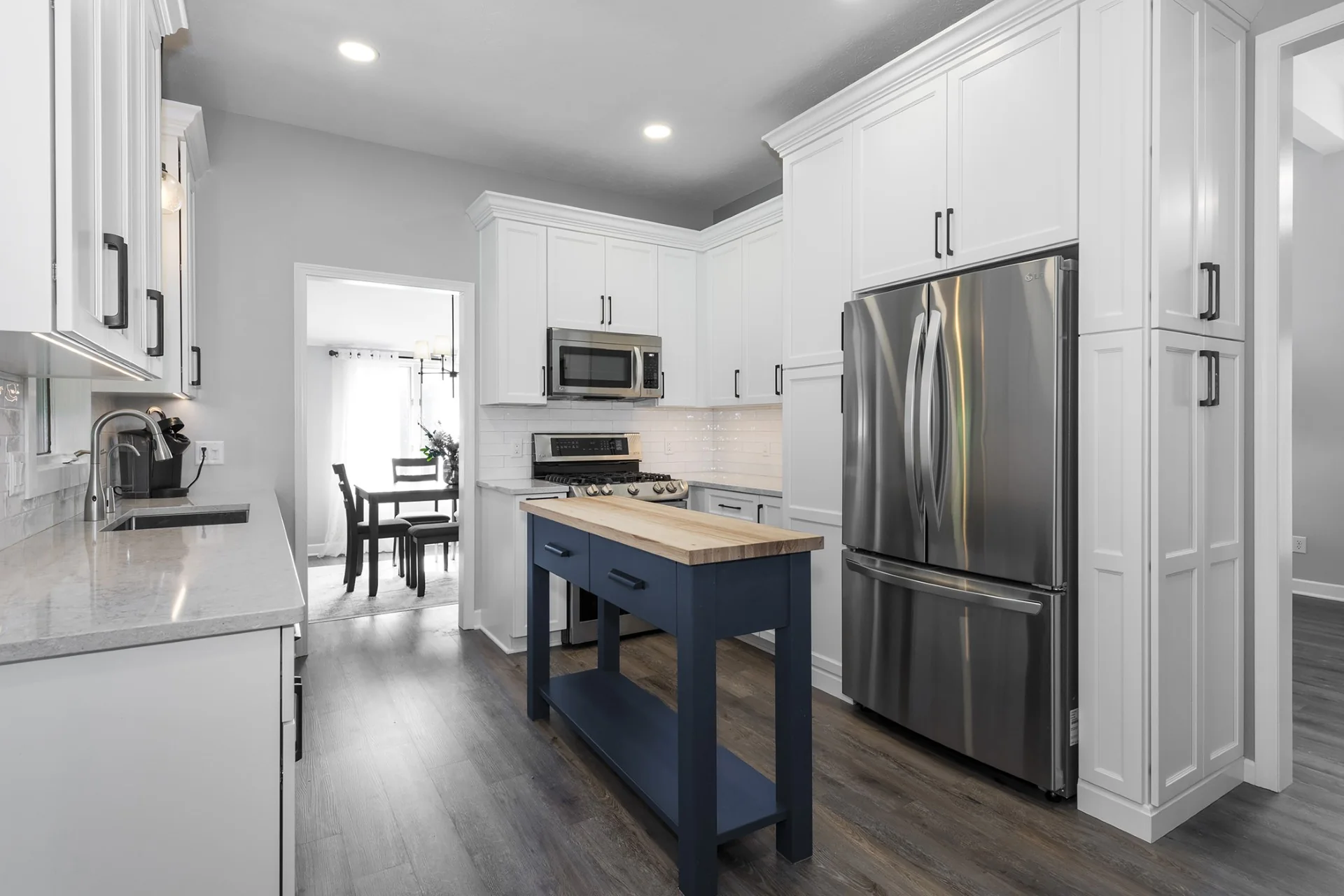 White kitchen cabinetry surrounding the range and refrigerator