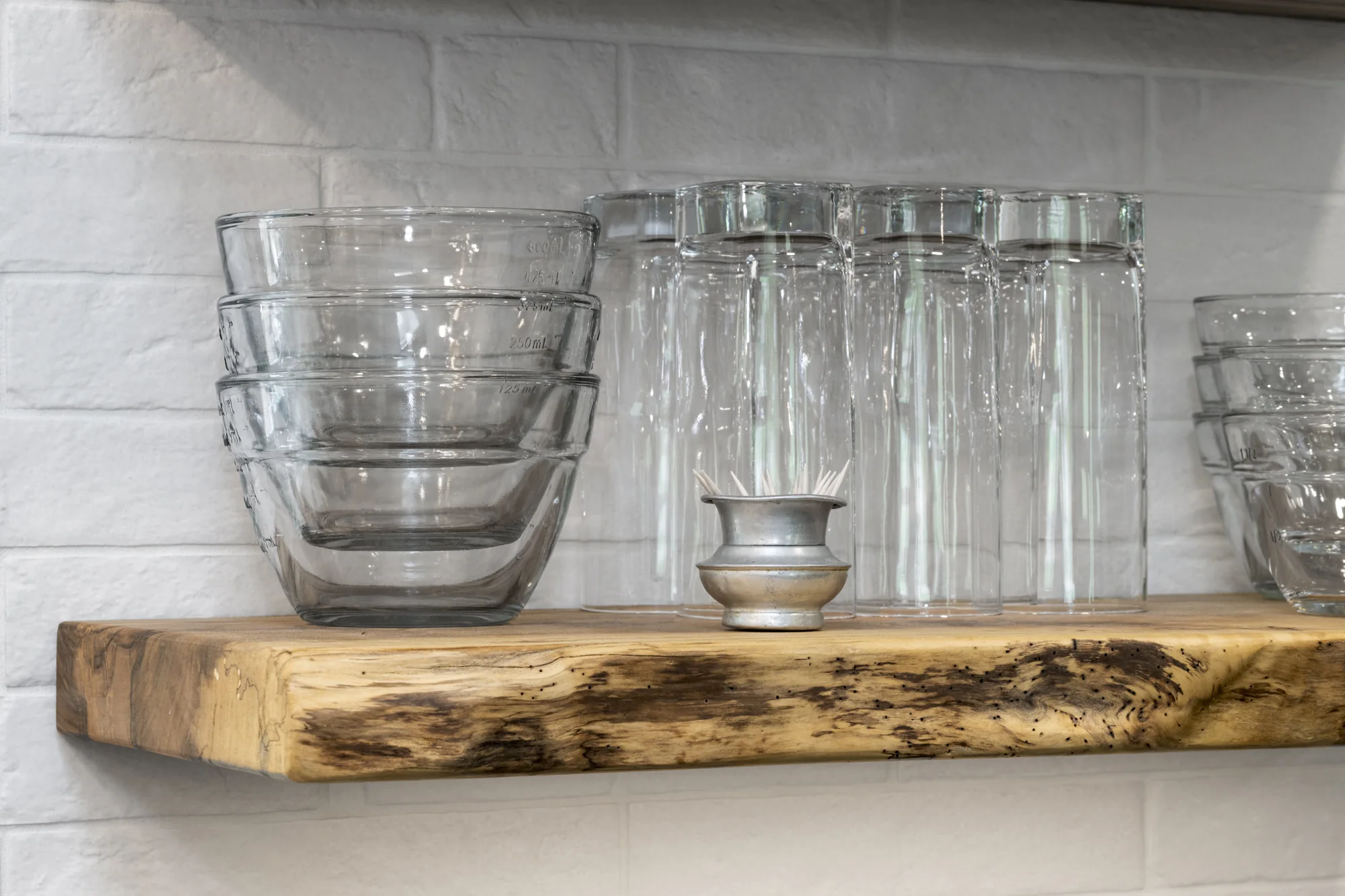 Live-edge wood shelf detail against the white backsplash